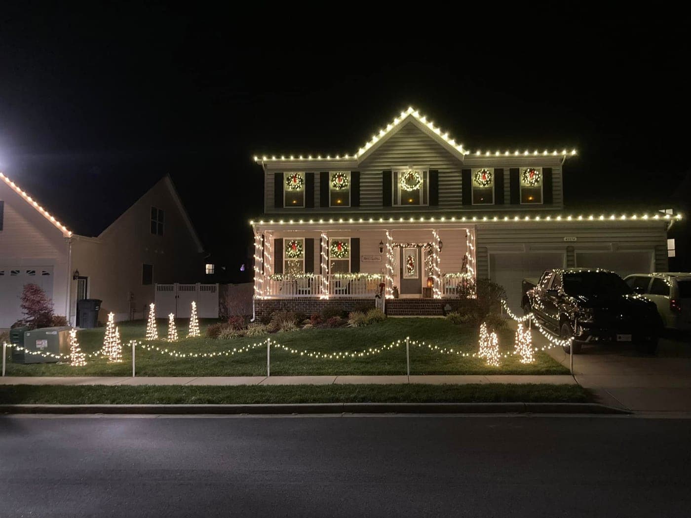 Holiday roofline lights with lit walkway trees on a Southern Maryland home